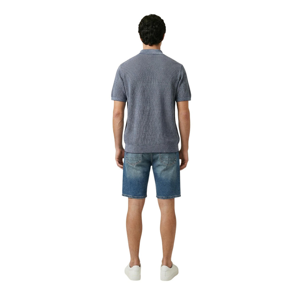 Back view of a man wearing a blue polo shirt featuring short sleeves and a collar on a white background.