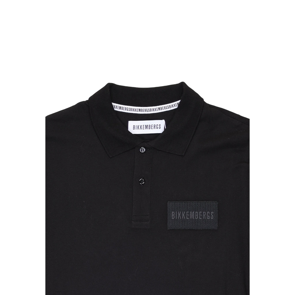 Close-up detail of the black polo shirt highlighting the collar and logo detail on a white background.