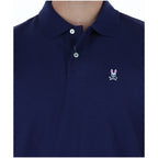 Detail close-up of the navy polo shirt highlighting the collar, buttons, and logo embroidery on a white background.