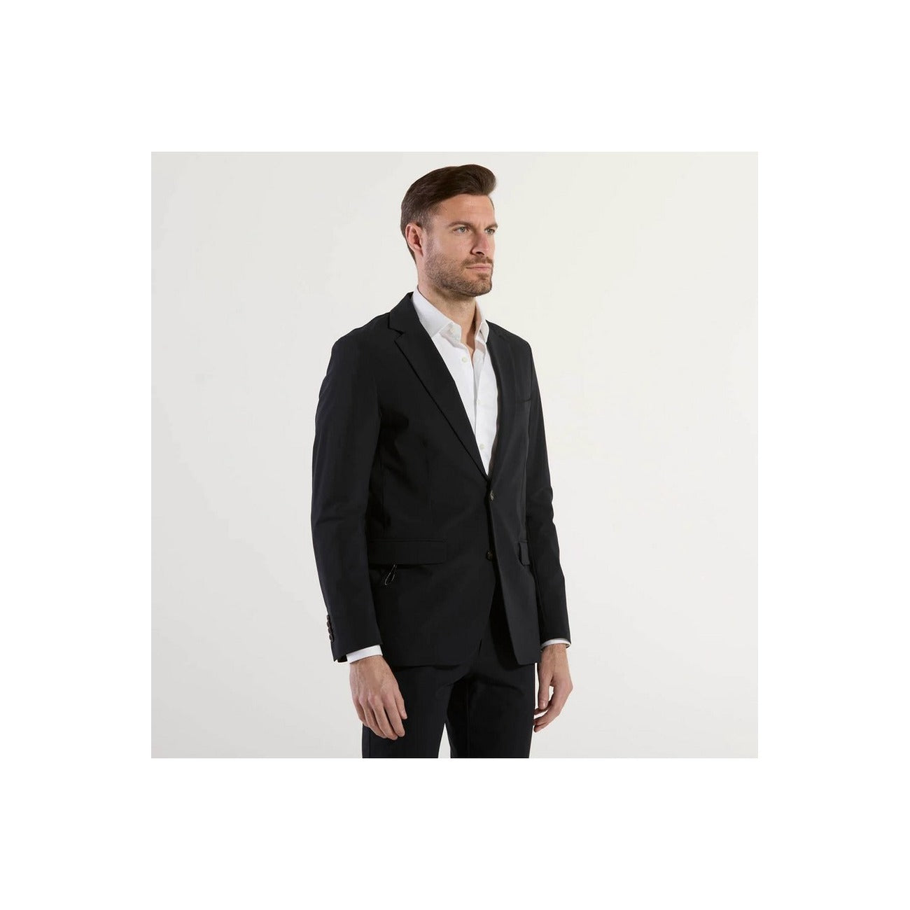 Lifestyle shot of a man in a tailored black suit with a white shirt against a white background