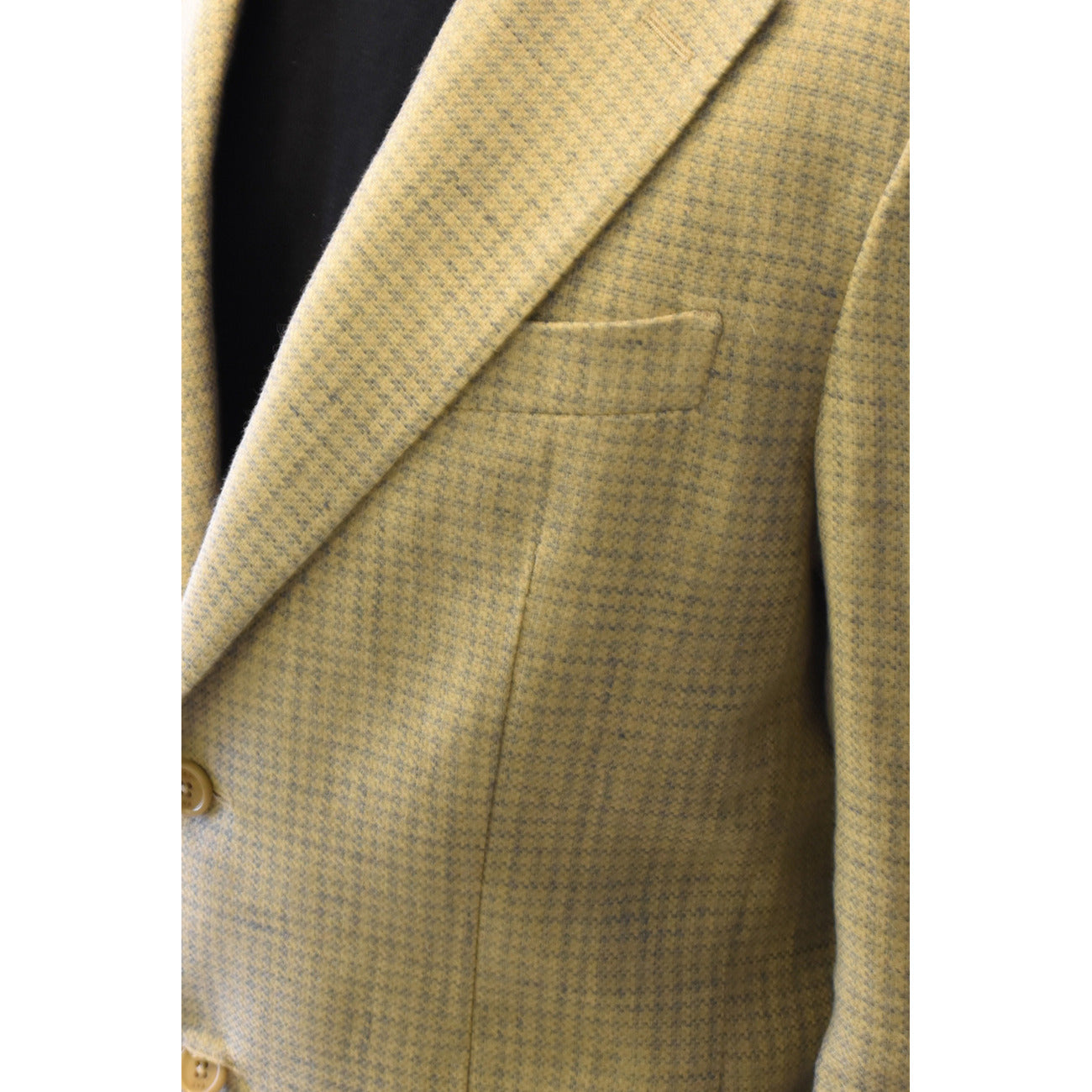 Close-up detail of the blazer's textured fabric and pocket on a white background