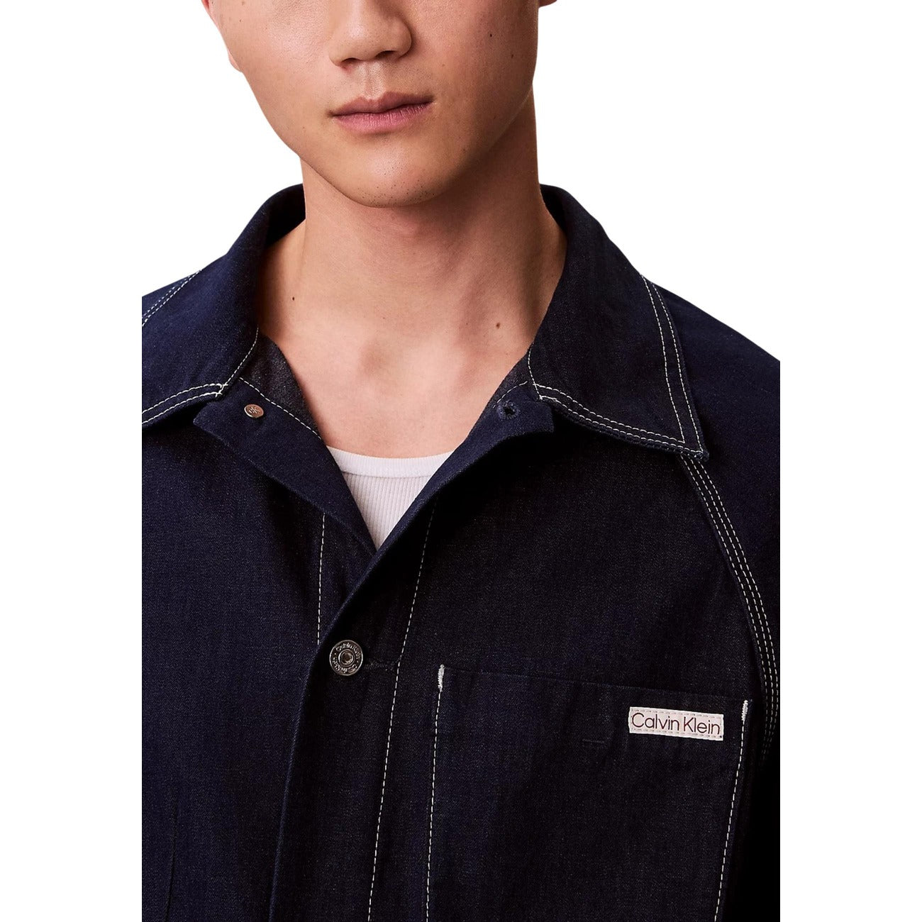 Detail close-up of a navy denim blazer highlighting the zipper, collar, and label on a white background.