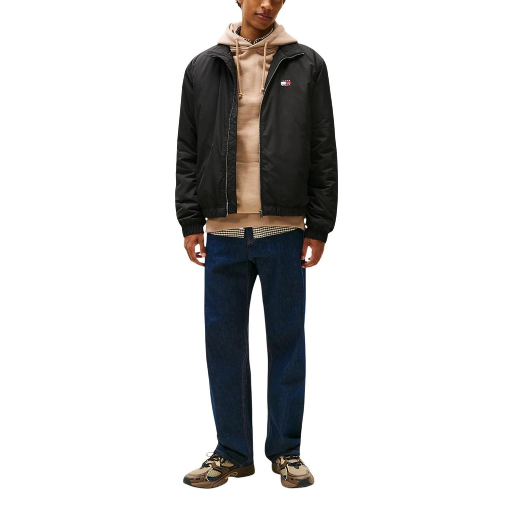 Lifestyle shot of a model in the black Tommy Hilfiger Jeans blazer styled with a casual outfit on a white background