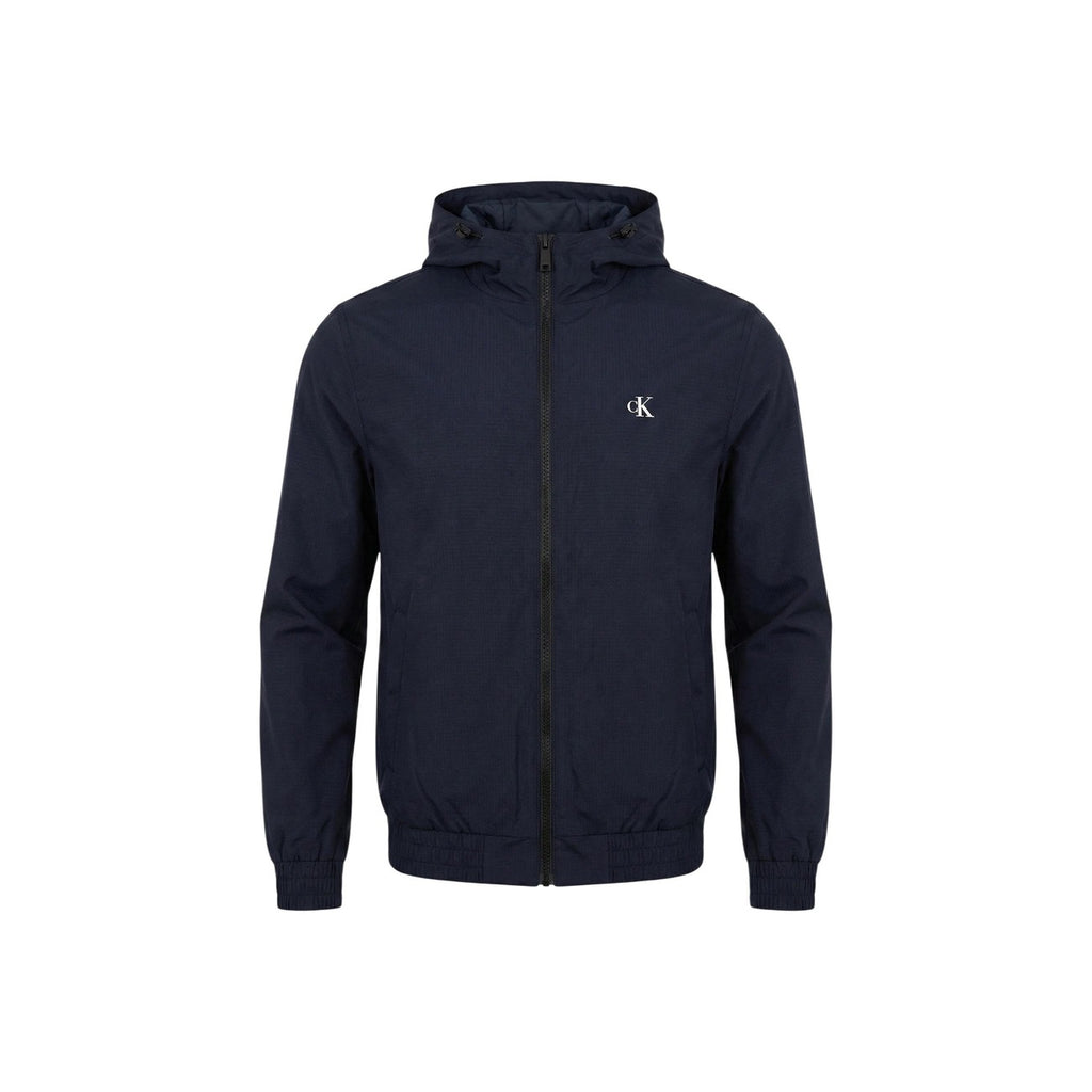 Close-up detail of a navy hoodie featuring a logo and zipper against a white background.