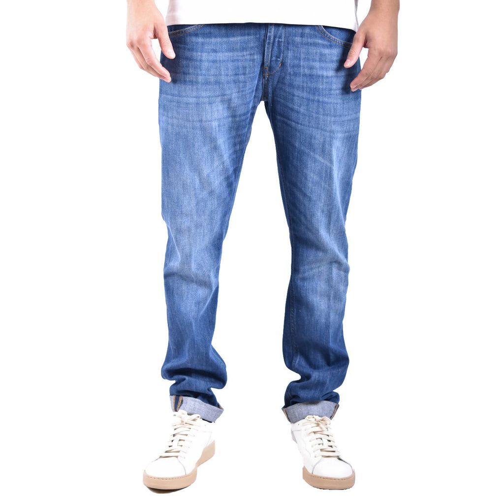 Lifestyle shot of a person wearing blue Dondup jeans with a casual fit and sneakers in a studio setting.