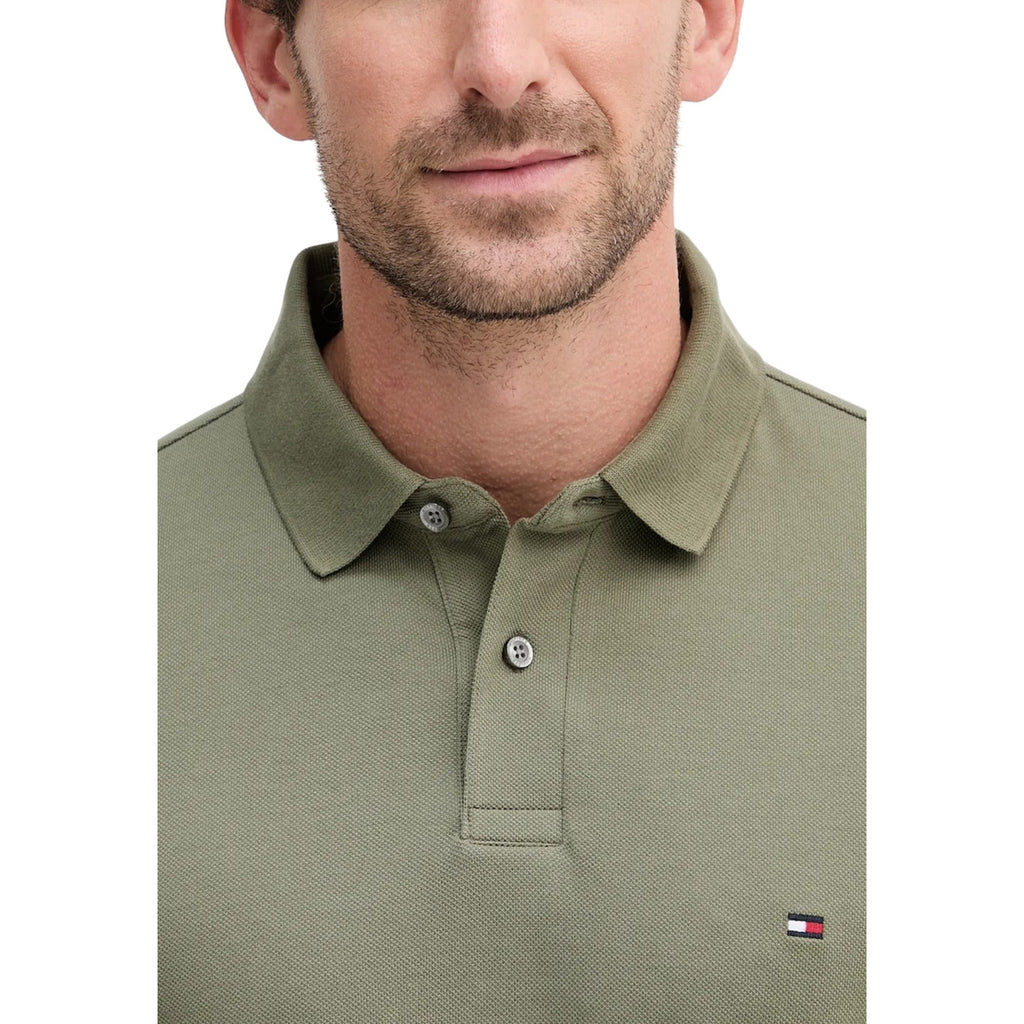 Detail close-up of the green long-sleeve polo highlighting the logo and collar features on a white background.