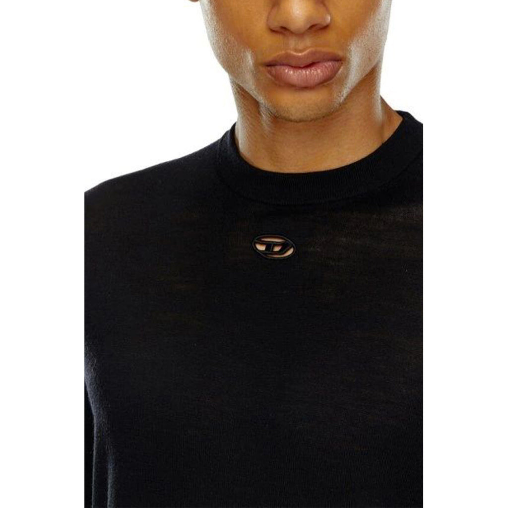 Detail close-up of the black sweater's neck with brooch on a white background