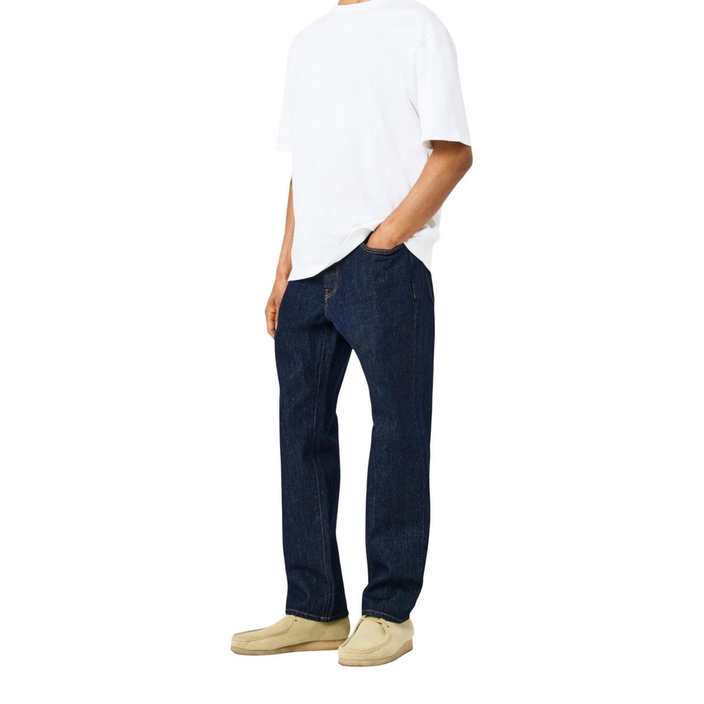 Lifestyle shot of a man in a white t-shirt wearing blue jeans, showcasing a comfortable fit.