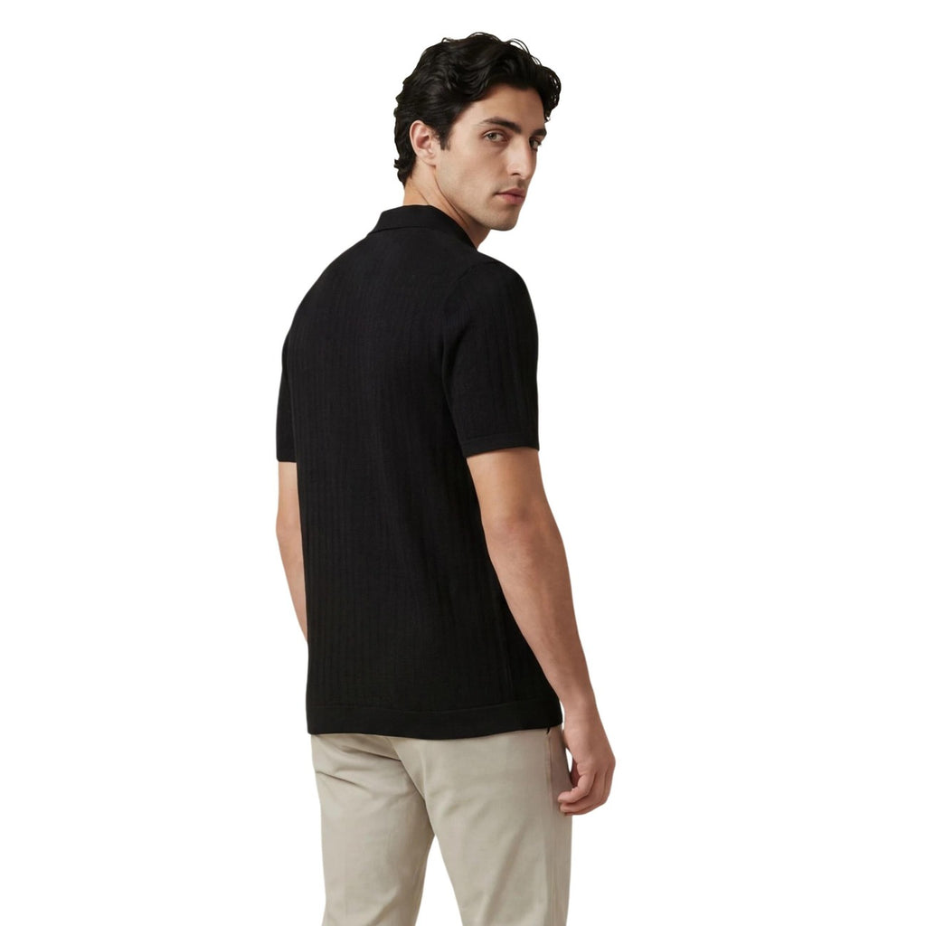Back view of the black polo shirt showcasing short sleeves and a collar.