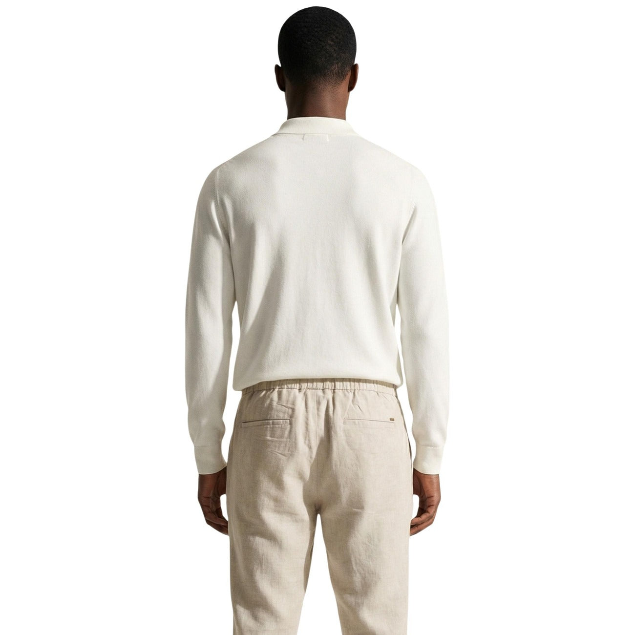 Back view of a man in a cream sweater with long sleeves and a classic collar.
