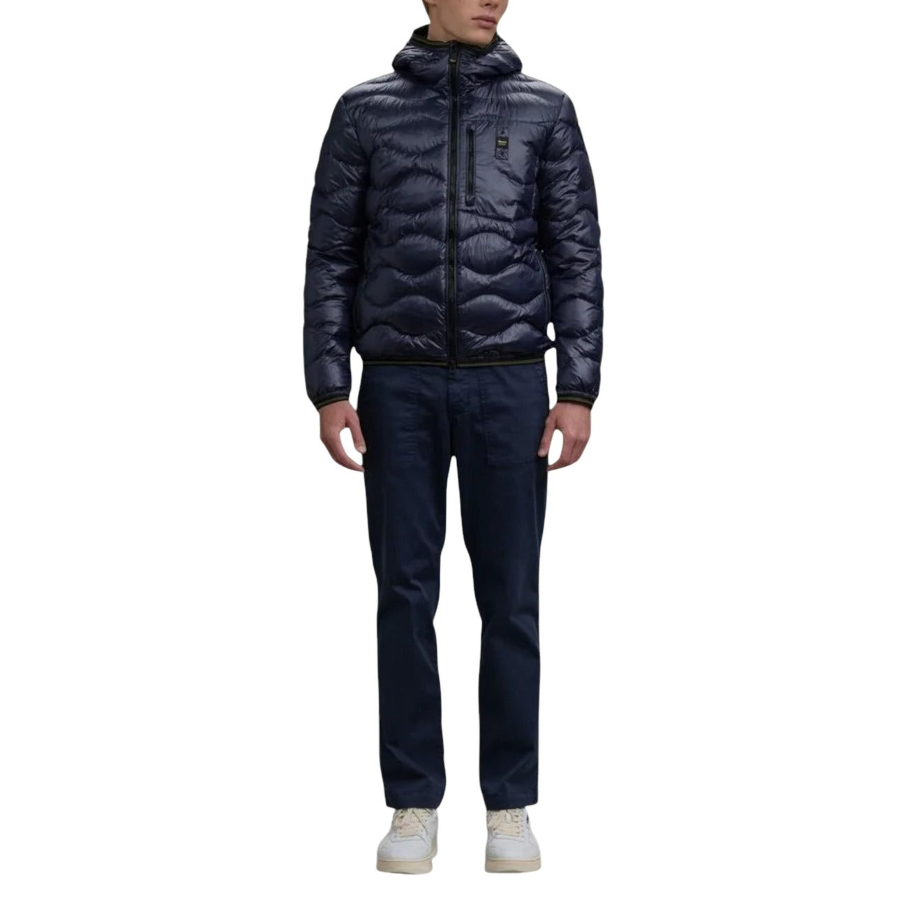 Lifestyle shot of a model wearing the navy puffer jacket with a hood and zipper closure in a studio setting.