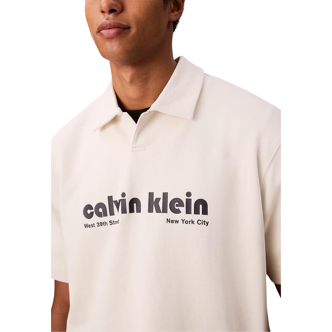 Close-up detail of a beige polo shirt's collar and logo print on a white background.