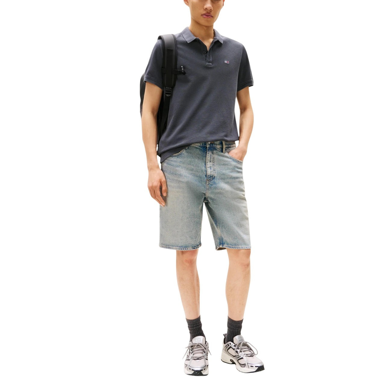 Lifestyle shot of a man wearing a gray polo and shorts, highlighting a casual outfit with sneakers.