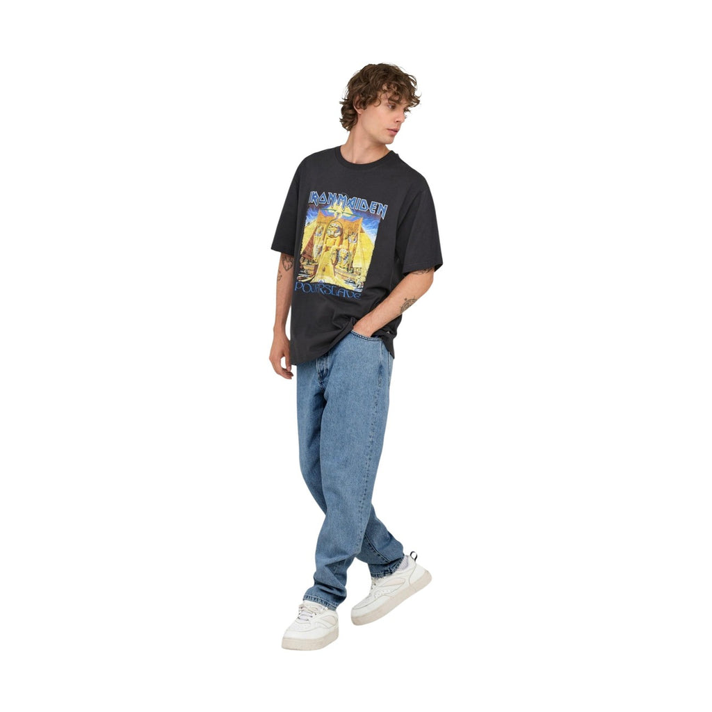 Side view of a person in light blue jeans and a graphic t-shirt, featuring white sneakers against a white background.