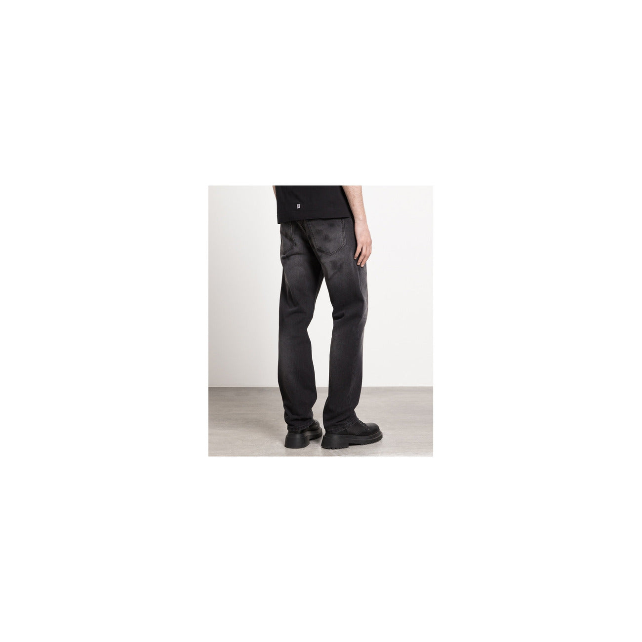 Lifestyle shot of the grey Givenchy men's jeans with a straight leg and high waist against a natural background.