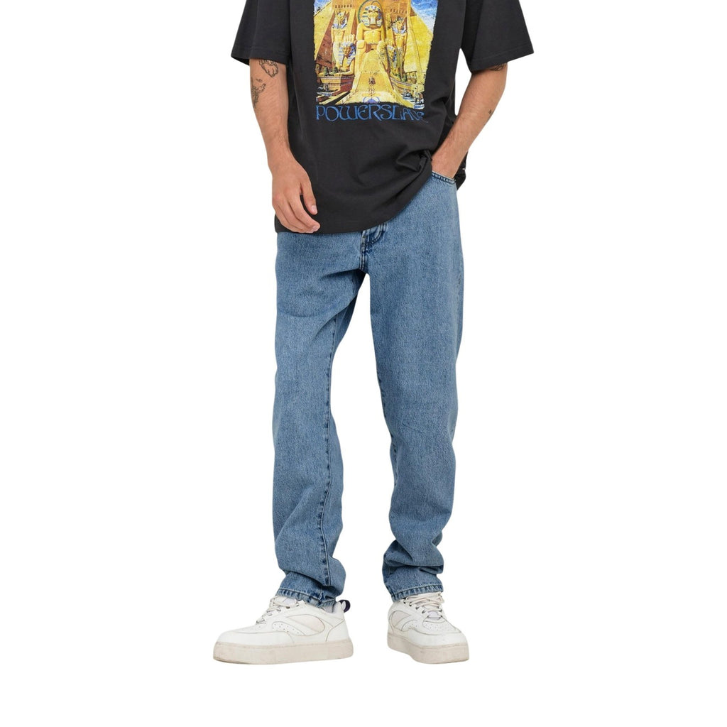 Lifestyle shot of a person wearing light blue jeans and a graphic t-shirt against a white background.