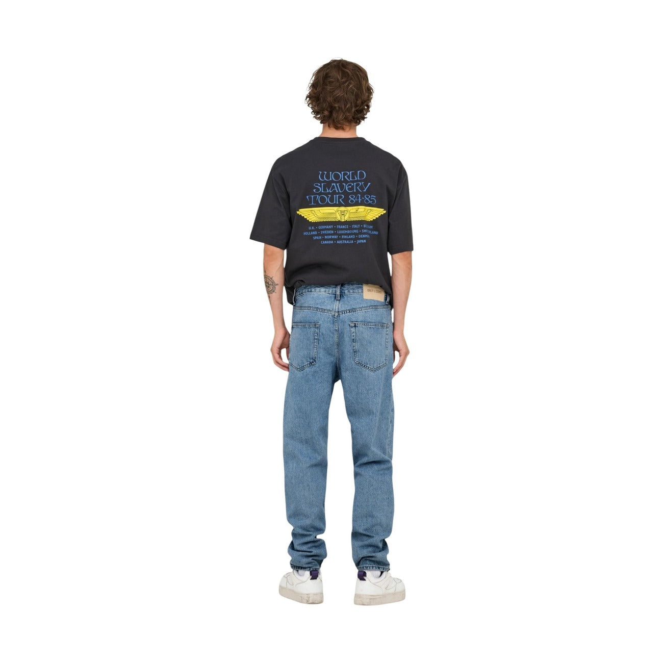 Back view of a person in light blue jeans and a graphic t-shirt on a white background.