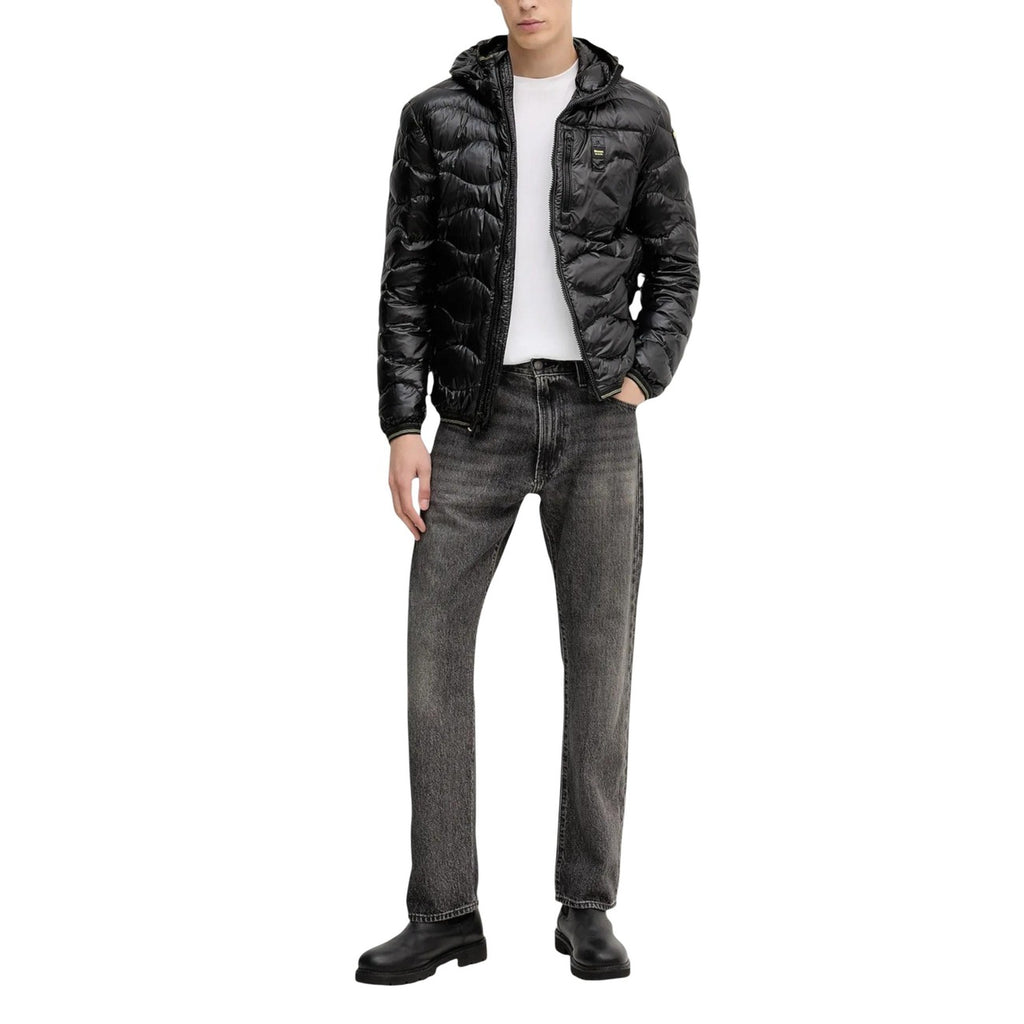 Lifestyle shot of a man wearing a black puffer jacket with a hood and quilted design in a studio.