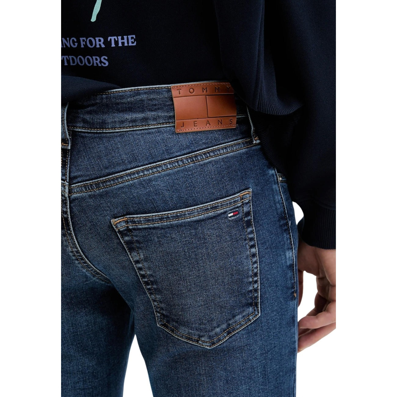 Detail close-up of the back of blue jeans showing back pockets and leather patch on a white background.