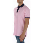 Side view of the pink polo shirt with collared design and short sleeves.