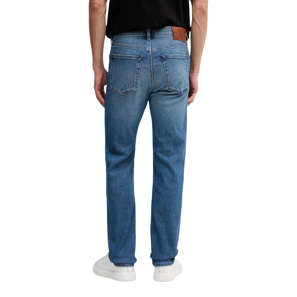 Front view of a man in a casual outfit with blue jeans, graphic t-shirt, and sneakers on a white background
