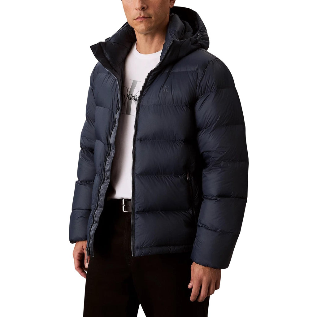 Lifestyle shot of a navy puffer jacket featuring a hood and zipper closure against a white background.