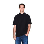 Lifestyle shot of a black polo shirt on a model, highlighting short sleeves and a collar in a studio setting.
