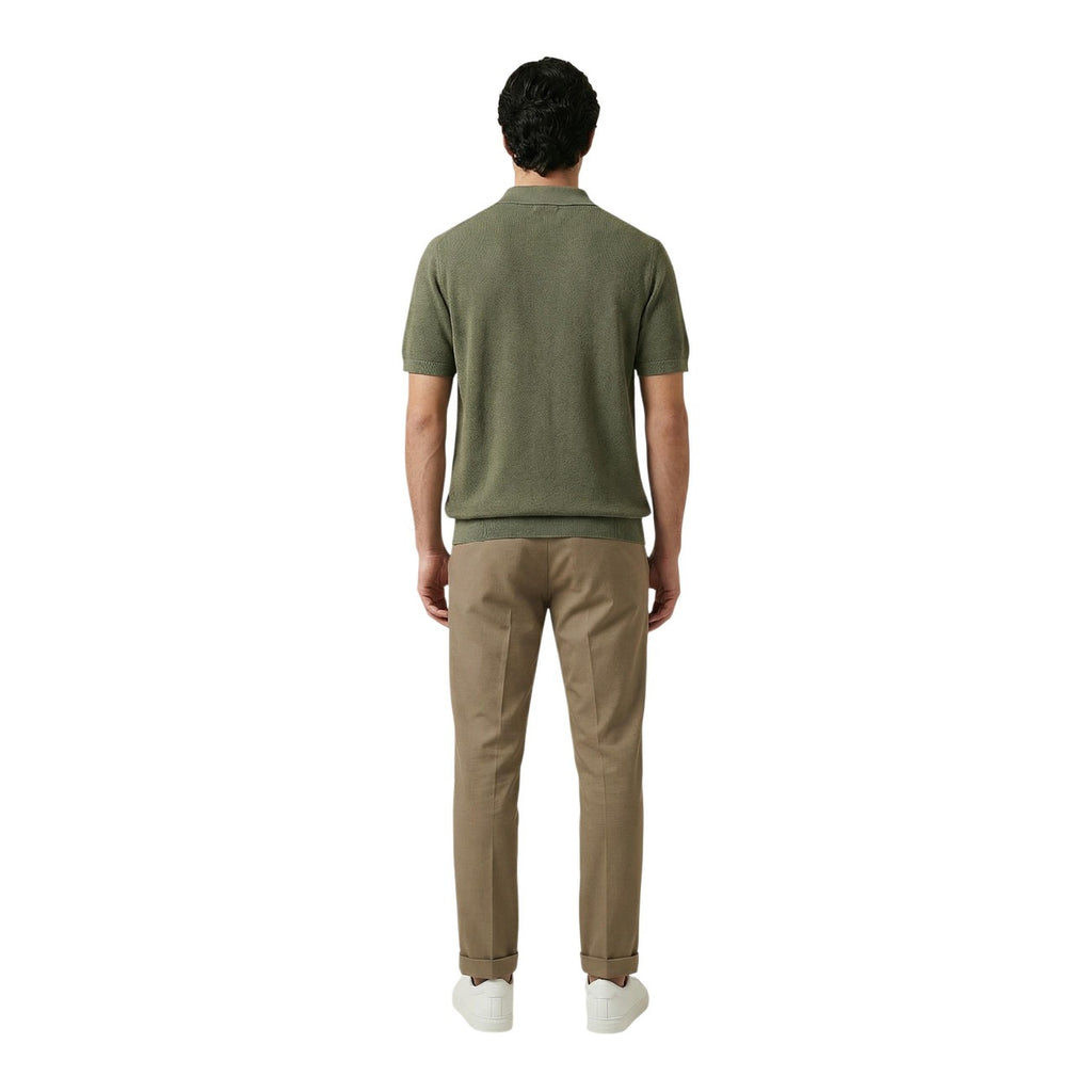 Back view of a man wearing a green polo shirt with short sleeves and collar on a white background.