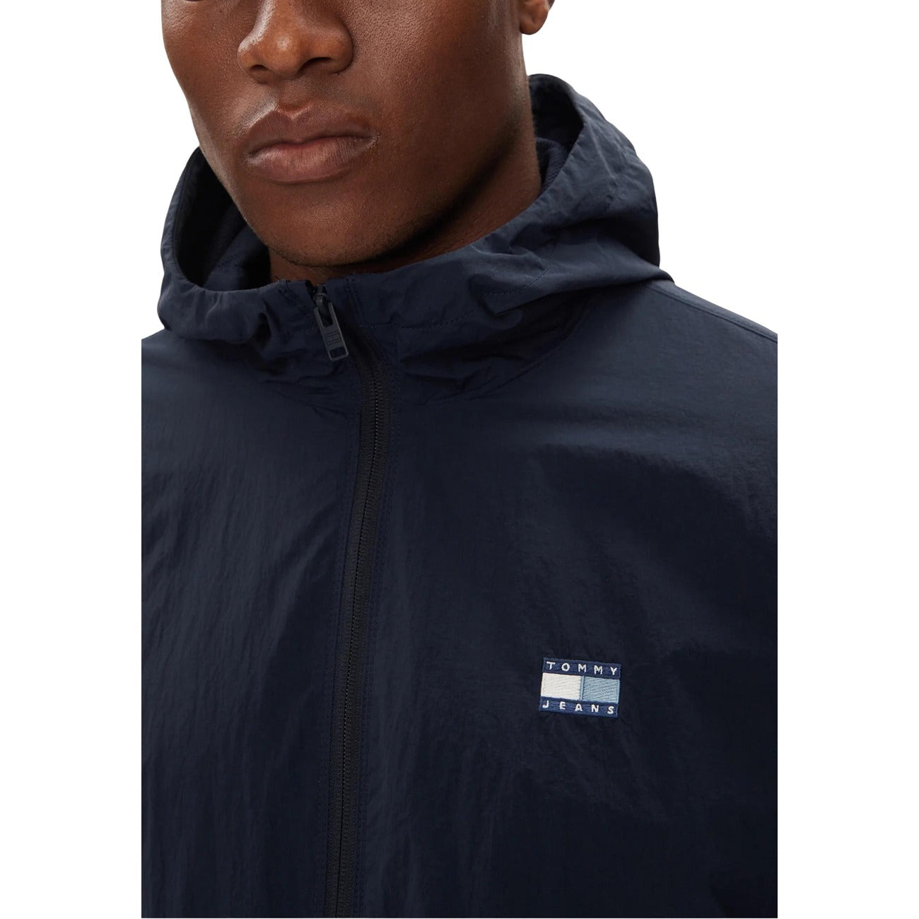 Detail close-up of a navy blazer showcasing the zipper and logo patch.