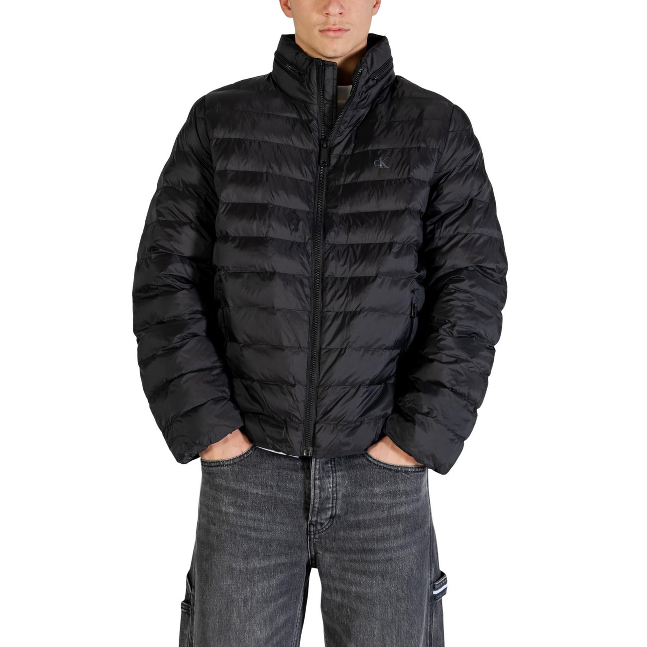 Lifestyle shot of a man wearing a black puffer jacket with zipper closure and pockets in a studio setting.