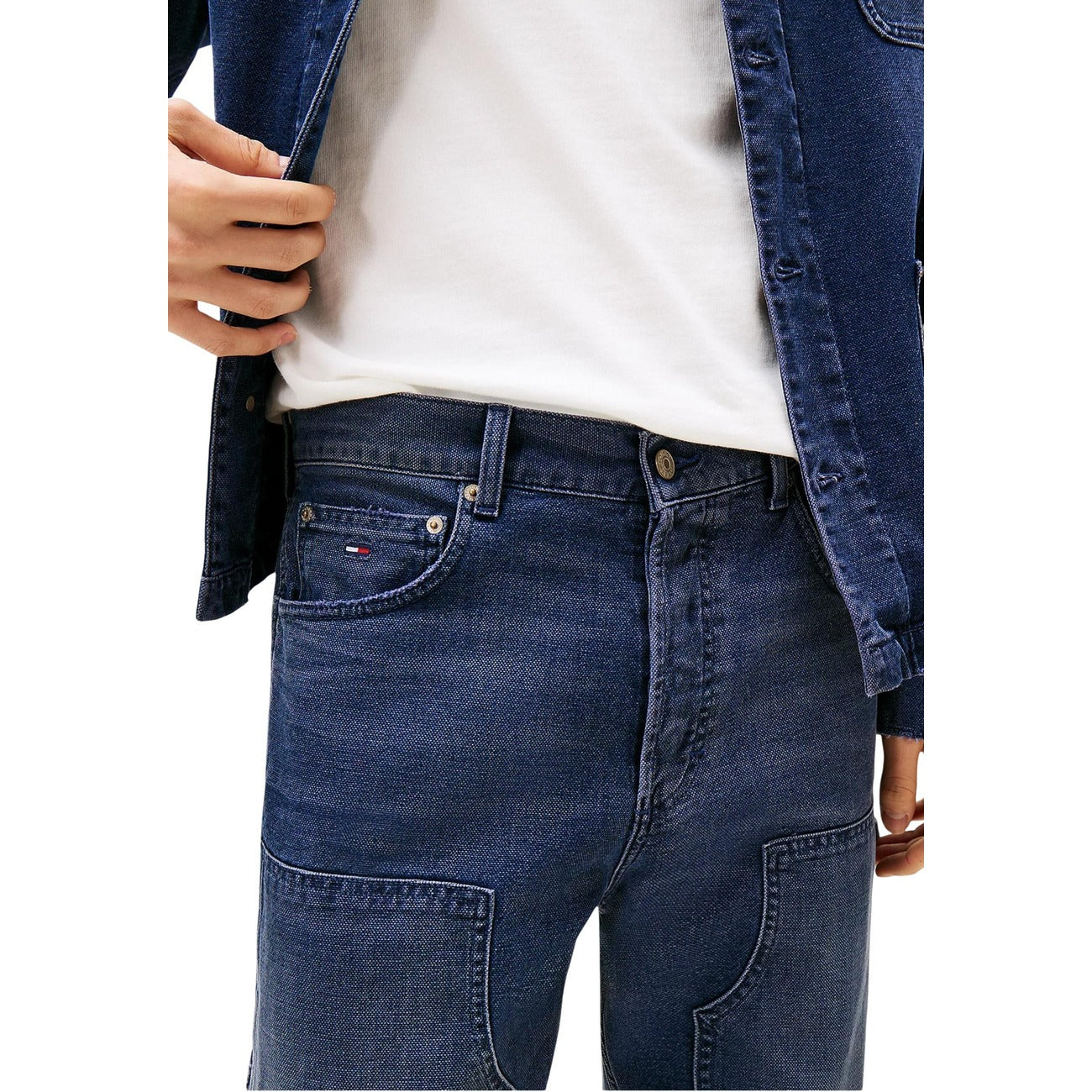 Close-up detail of blue jeans with a zipper fly and button closure on a white background.