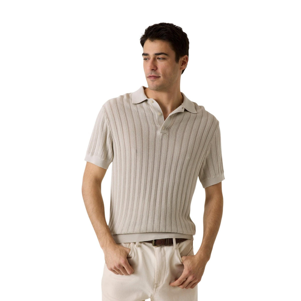 Lifestyle shot of a beige polo shirt with short sleeves and collar on a white background.